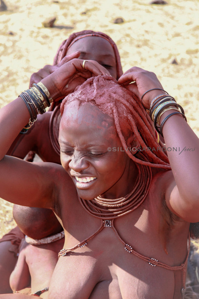 Expression of the young Himba woman who arranges the appearance and her hair, Opuwo, Namibia