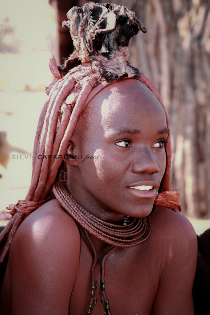 Young Himba girl portrait with her typical skin and hair colors, Kamanjab, Namibia